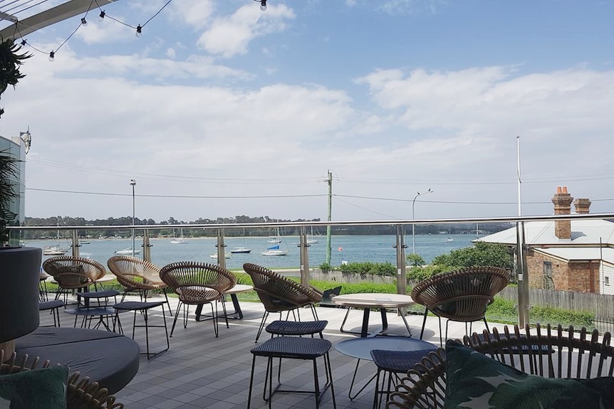 outdoor dining area facing the water with yachts in the distance