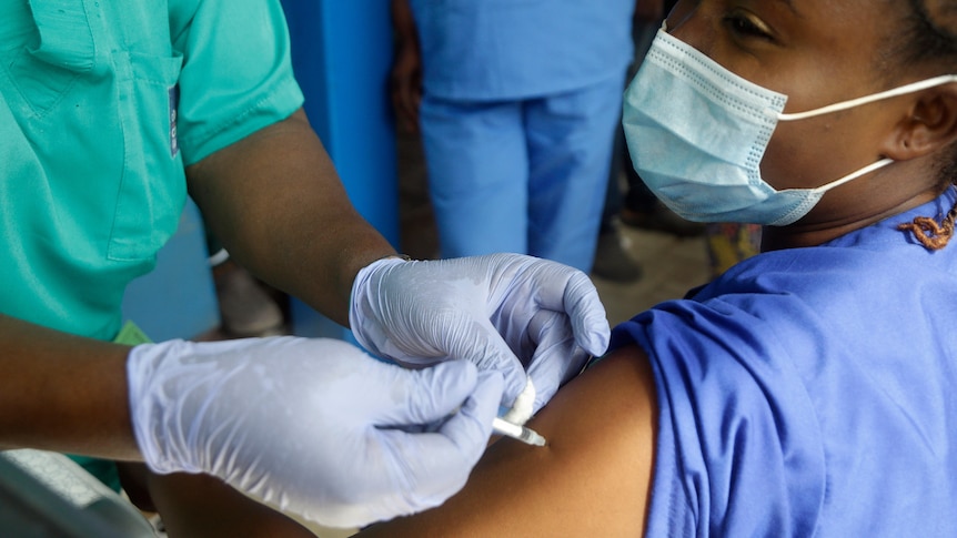     Una lavoratrice ospedaliera riceve le vaccinazioni contro il virus Corona al braccio.