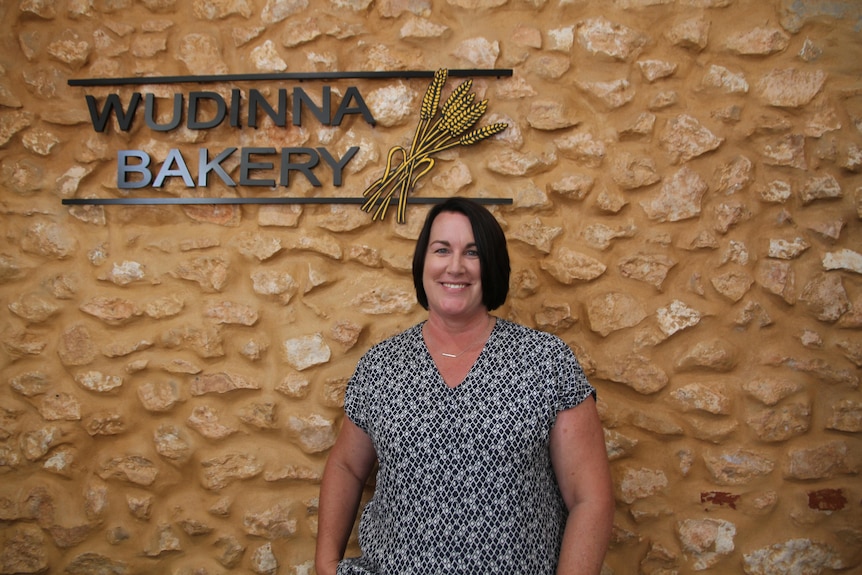 Wudinna bakery sign, smiling, black and white patterned top, brick wall