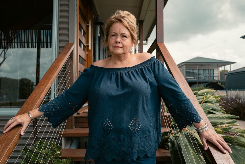 A woman standing on the front stairs of a home.