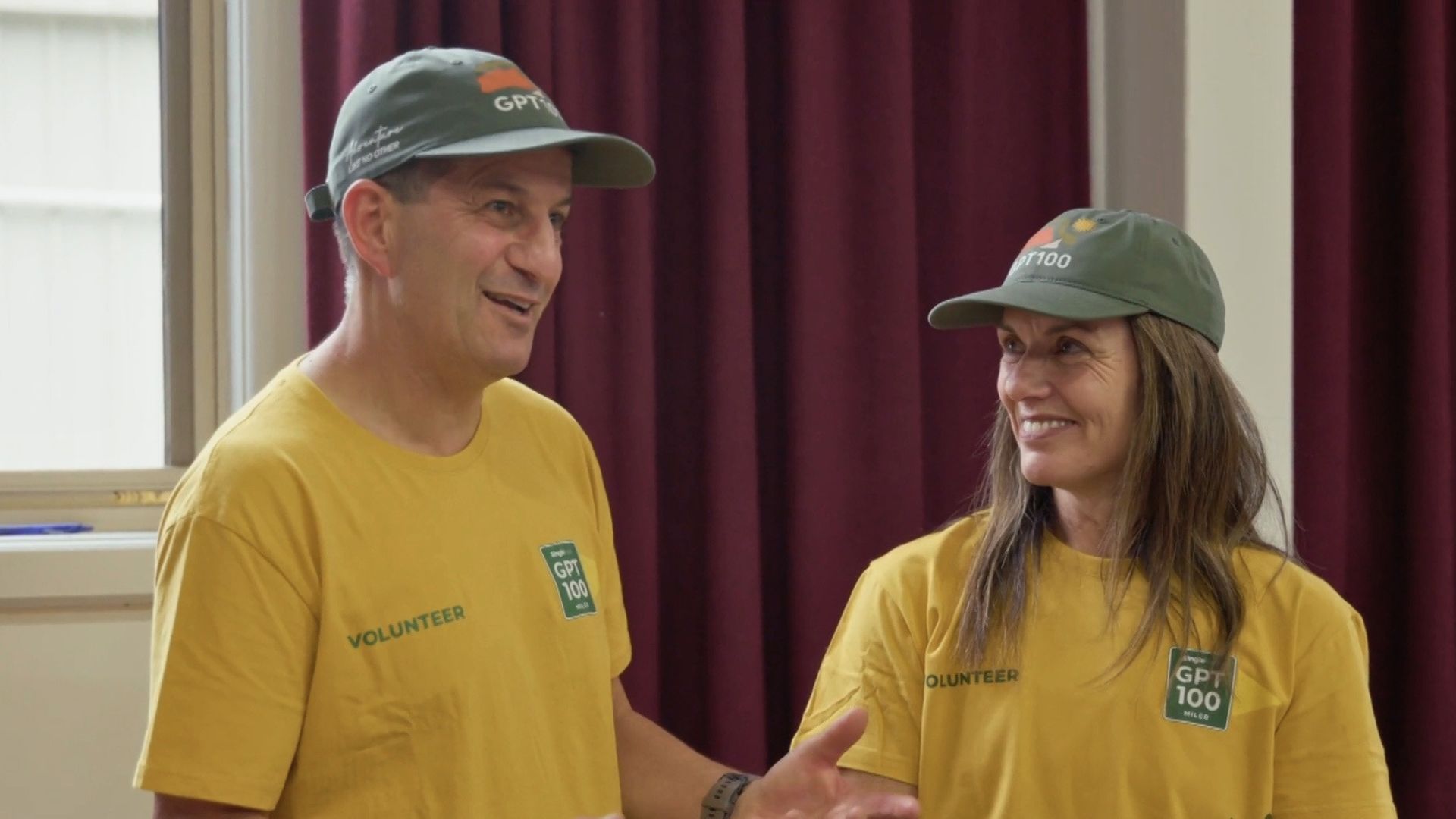 At night, Greg and Nicole Kew cross a finish line with their arms in the air.