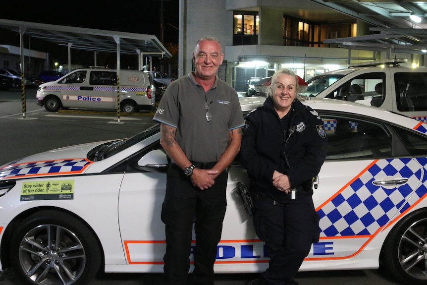 Sergeant Megan Ward and clinical nurse consultant Simon Daniels stand next to a police car.