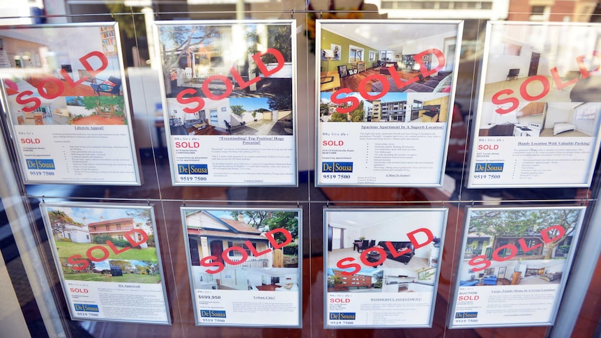 A window in a Sydney real estate agent shows properties sold.