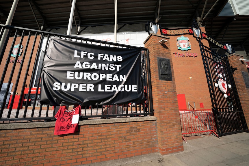 A black banner with white writing protesting a European Super League hangs on railings outside Liverpool's home ground