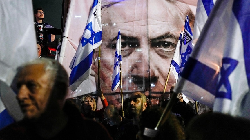 A large image of Netayahu's face, partially obscured by flags and protesters