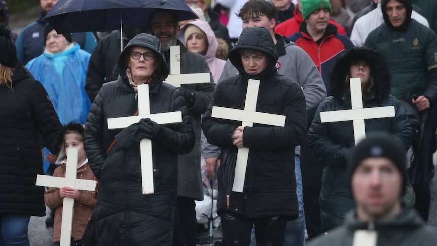 People take part in a march holding crosses to commemorate the victims of Bloody Sunday