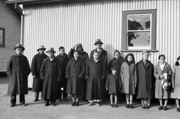 A group of civilian Japanese internees in front of a building.