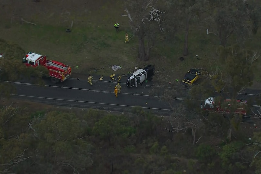 An aerial view of a crash site with multiple damaged vehicles and fire trucks in view.