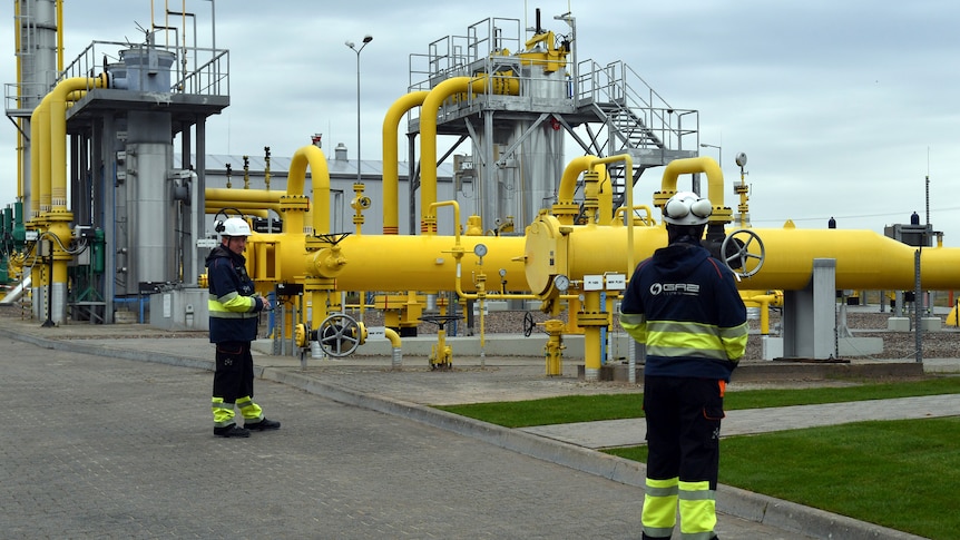 Workers stand near the pipelines during an opening ceremony of the Baltic Pipe in Budno, Poland.