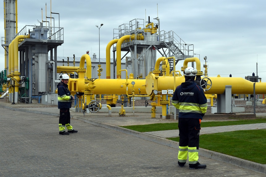 Workers stand near the pipelines during an opening ceremony of the Baltic Pipe in Budno, Poland.