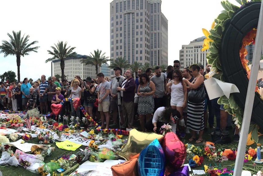 People gather around flowers, signs and balloons assembled as a memorial for the people who died at Pulse nightclub