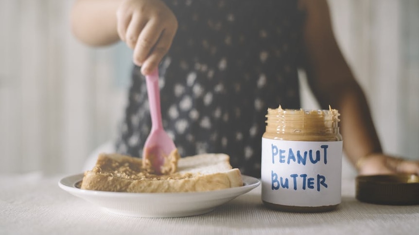 A person putting peanut butter on bread.