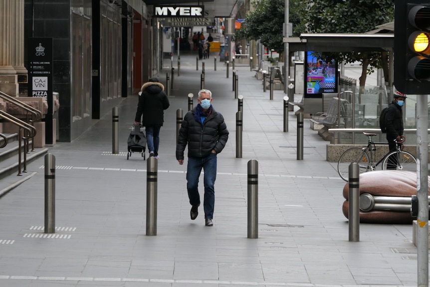 A man in a mask walks down an empty street.