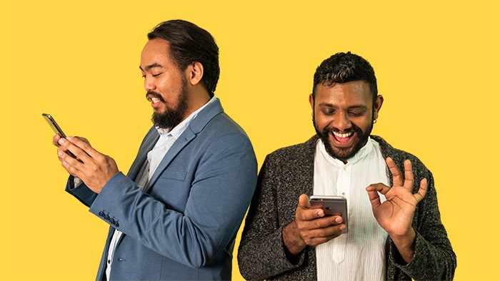 Photo of Matt Kerr and Shahmen Suku interacting on their phones, they experience racism via gay dating apps like Grindr