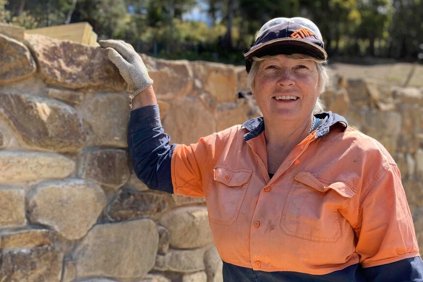 Lyn Stedman wearing high vis, posing with a stone wall.