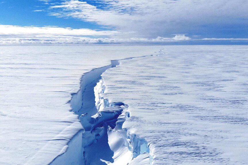 A huge crack emerges in a thick sheet of ice so large it stretches into the horizon.