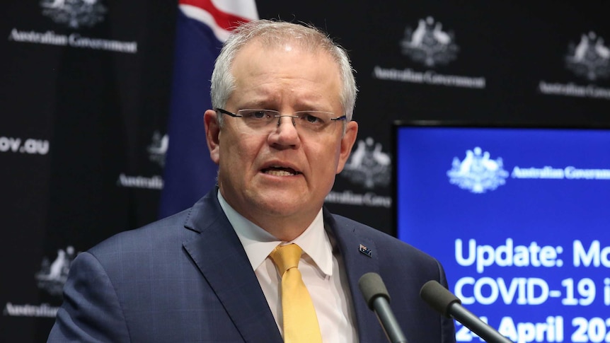 Scott Morrison speaks at a press conference with an Australian flag behind him