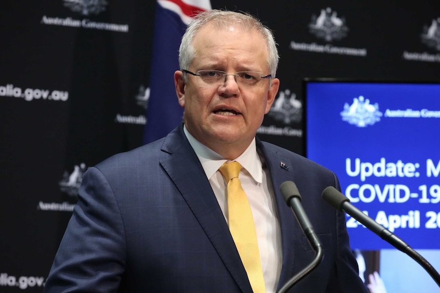 Scott Morrison speaks at a press conference with an Australian flag behind him.