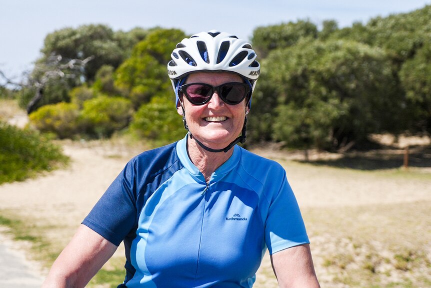 A smiling, older woman in cycling gear.