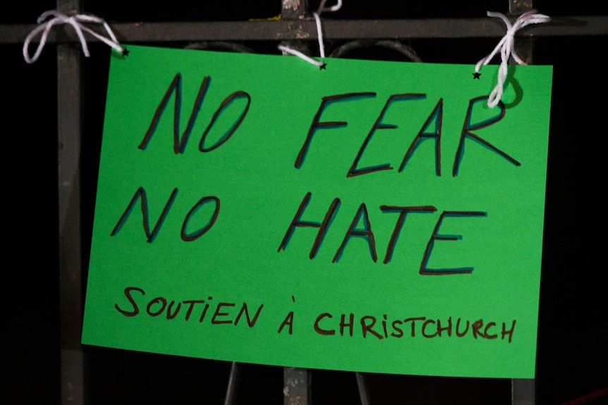 A tied up green sign saying "No fear no hate soutien a Christchurch".