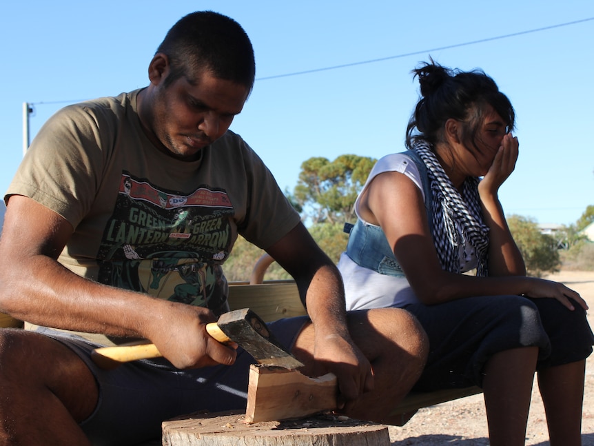 Teenagers learning techniques to carve boomerangs