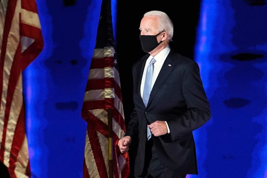 Joe Biden walks out for his acceptance speech wearing a mask after winning the US presidential election