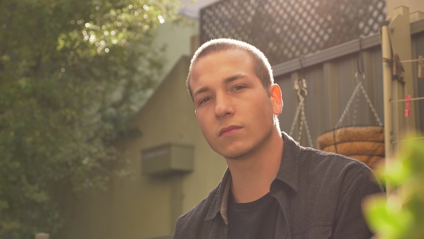 A man, Jordan Cassells, sits in his back patio.