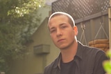 A man, Jordan Cassells, sits in his back patio.