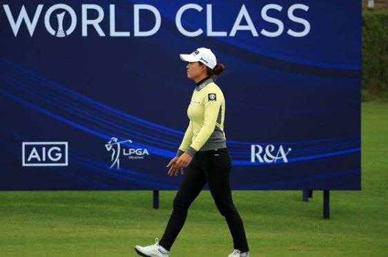A golfer walks past a sign at the Women's Open tournament in Scotland.