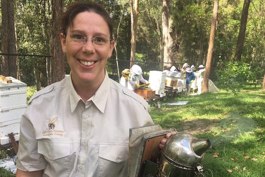 Gold Coast Amateur Beekeepers Society president Kathy Knox, with a smoker in front of hives on Queensland's Gold Coast.