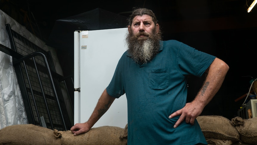 A man stands in front of a pile of sandbags.