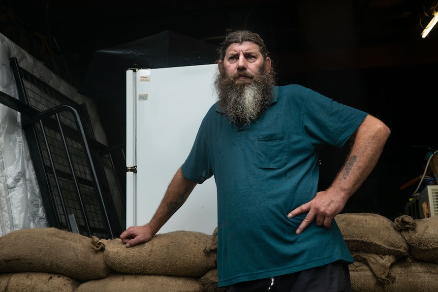 A man stands in front of a pile of sandbags.