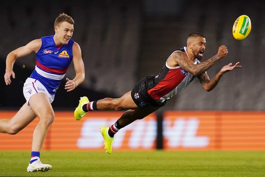 Bradley Hill is completely horizontal as he dives while handballing. Jackson Macrae gives chase behind him