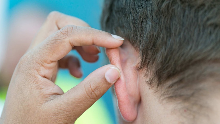 Person checking someone's ear for skin cancer