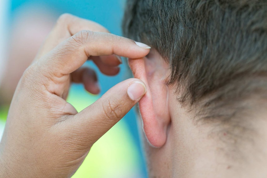 Person checking someone's ear for skin cancer