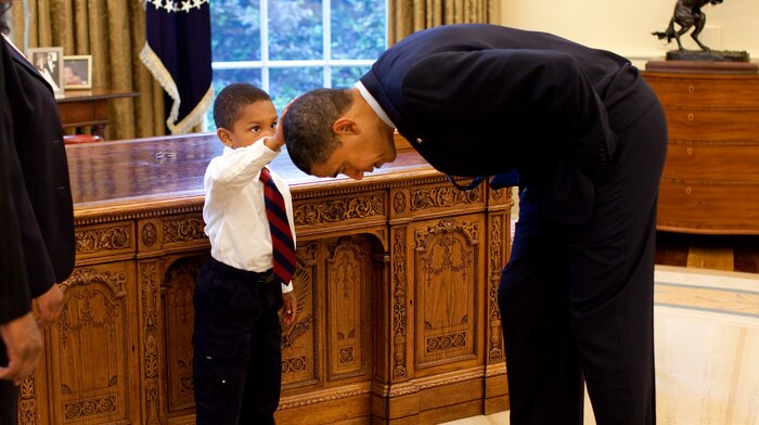 A White House staffer's son touches Barack Obama's head in the Oval Office