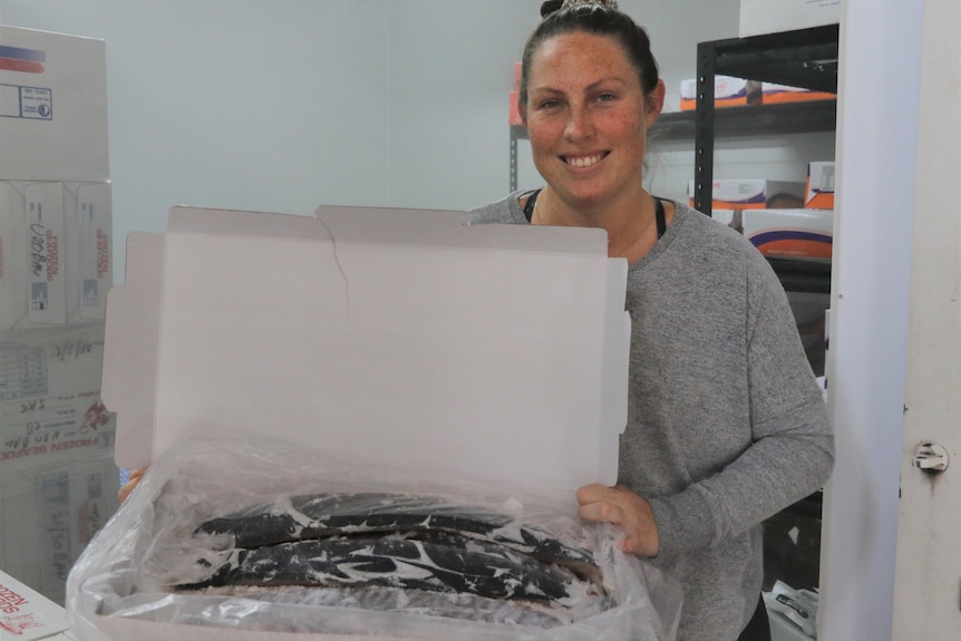 woman holding box of spanish mackerel