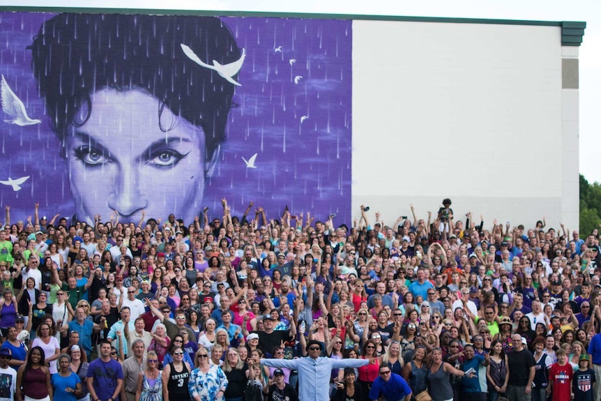 Crowd takes selfie in front of Prince mural