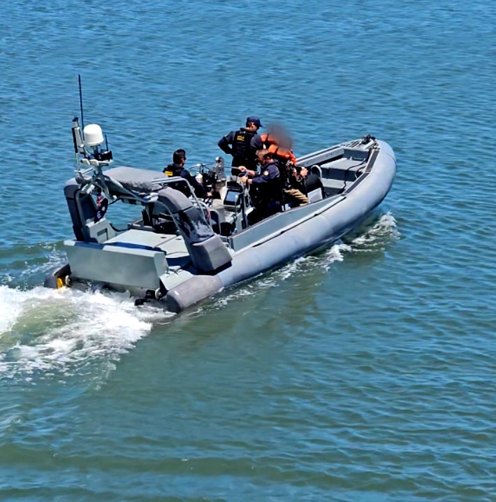 A rubber ducky style boat speeds off with men aboard.