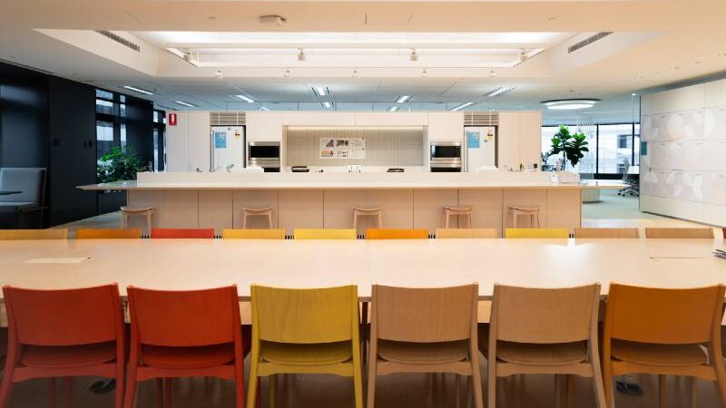 A row of coloured chairs in an empty office kitchen.
