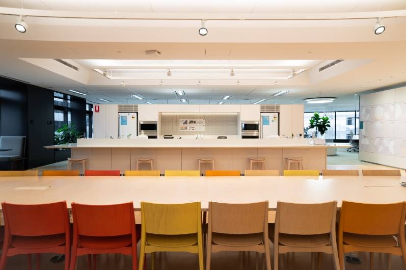 A row of coloured chairs in an empty office kitchen.