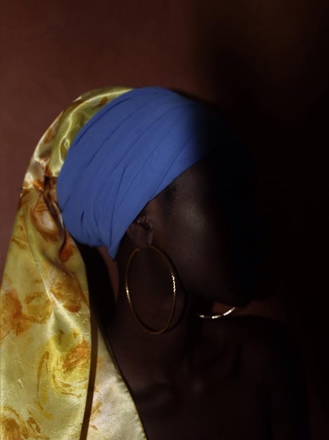 A black woman with a hoop earring and a head wrap in the style of the painting 'Girl with a pearl earring'
