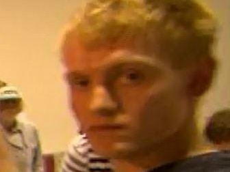 A grainy photo of a blond man looking towards the camera.