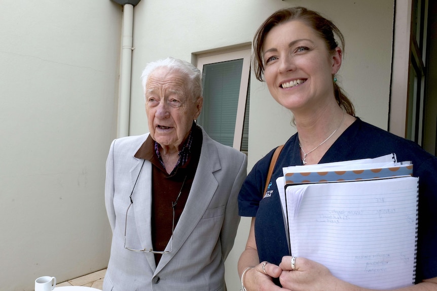 Kasia Bail holding a stack of papers next to an older man in a suit jacket.