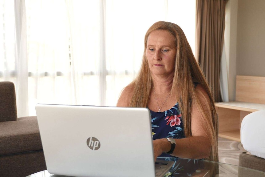 Katrina Walsh sitting at a desk looking at her laptop.