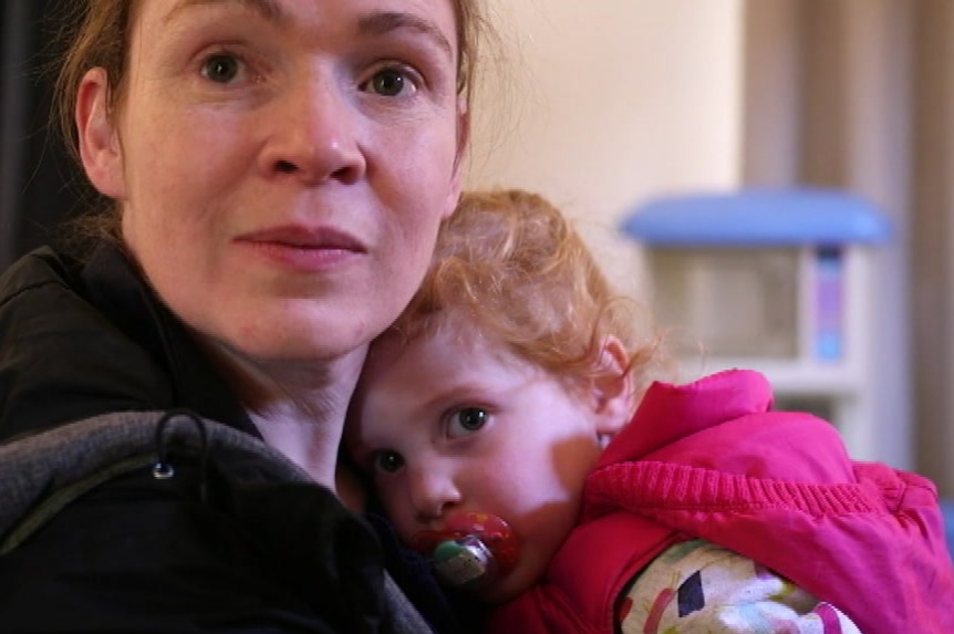 Alice Zsembery looking at the camera holding her daughter, Emily