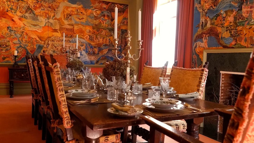 A set dining table in a room covered with murals