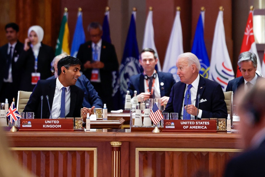 Rishi Sunak și Joe Biden stau unul lângă altul și se uită unul la altul în timpul întâlnirii.