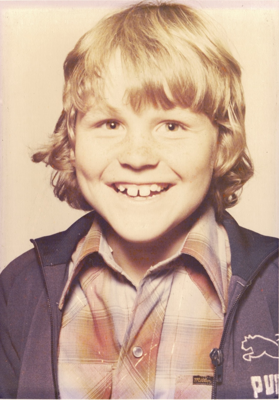 A young boy with a blonde hair smiles.