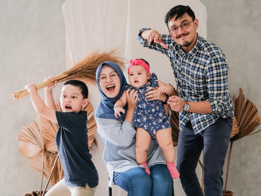 A mother, father and two children make funny faces in a family photo.